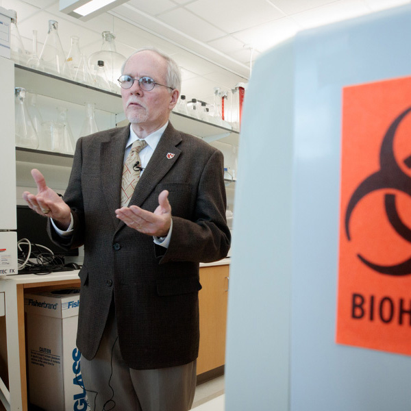 A man stands near a barrel with a biohazard symbol
