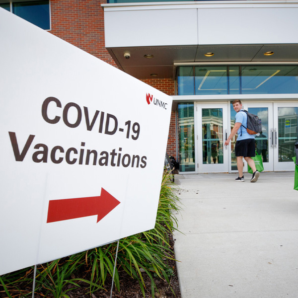A sign reading "COVID-19 vaccines" points to a nearby building