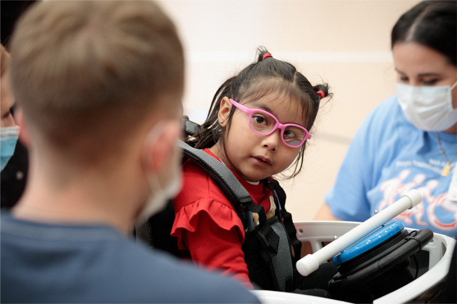 A young girl with glasses looks at a UNMC student