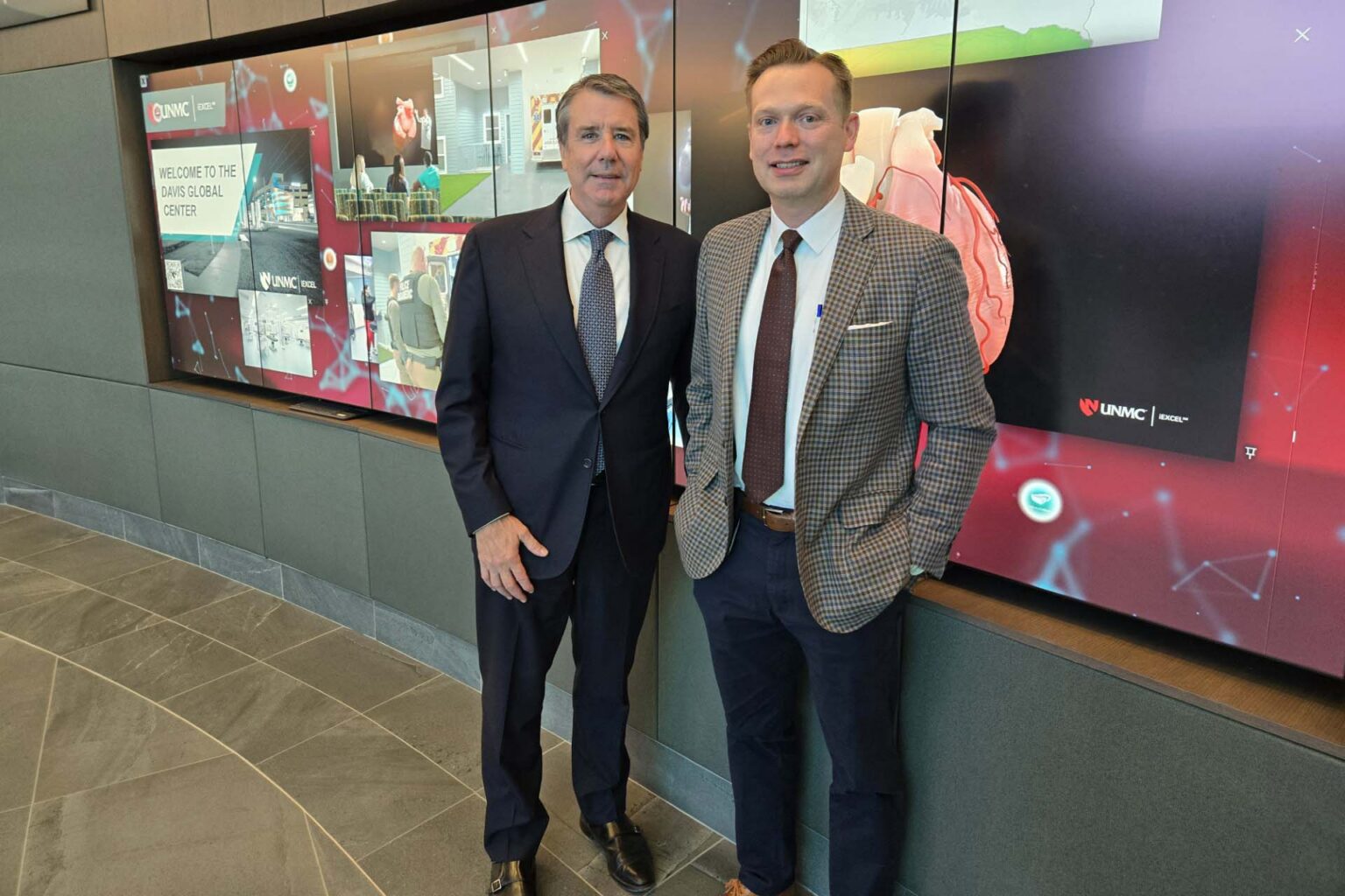 Brinker Harding and UNMC's Jeff Kratz standing in front of the iEXCEL iWALL during a visit of UNMC.  