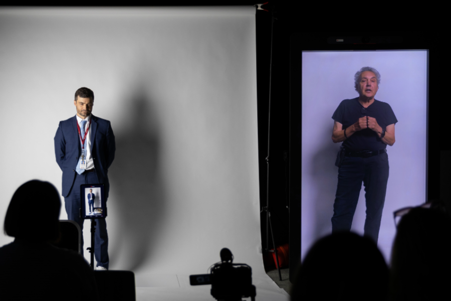 Michael Hollins stands in front of a white backdrop next to a holo box with Michael Masucci