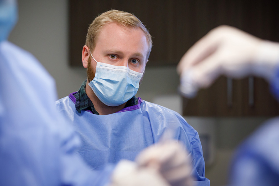 A man in a surgical mask observes procedures in an operating room