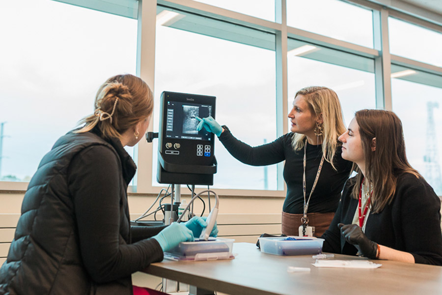 Two residents learn from a faculty instructor in the simulation lab at UNMC.