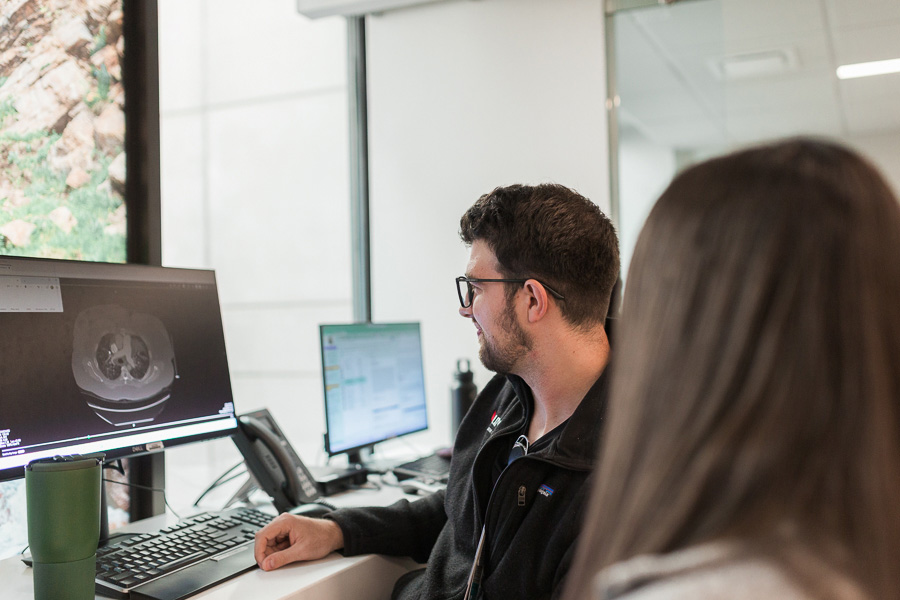 Two UNMC internal medicine residents work in front of a computer screen showing a scan.