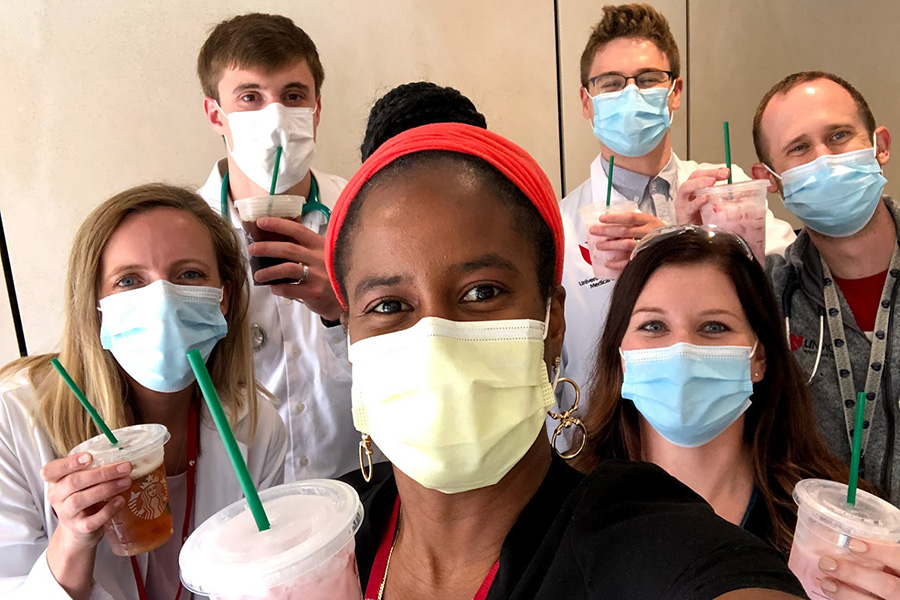 Dr. Jasmine Marcelin with a group of trainees, all wearing masks and holding drinks.