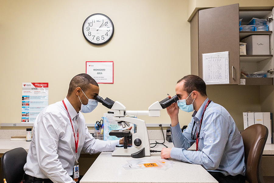 Residents looking at slides under a microscope at Midtown Clinic