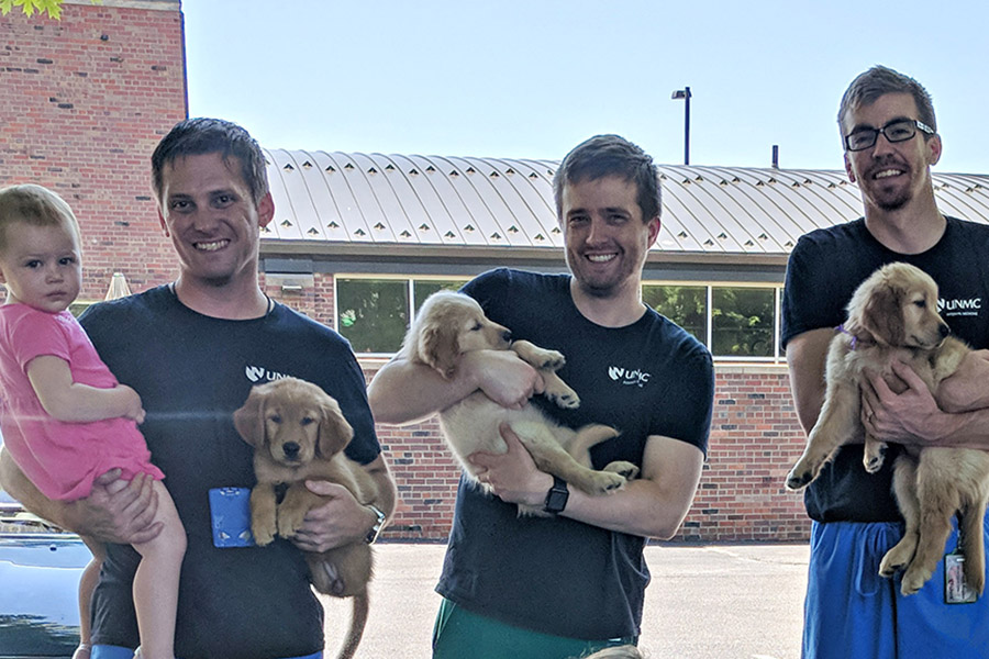 Internal Medicine residents snuggling with puppies outside of Midtown Clinic.
