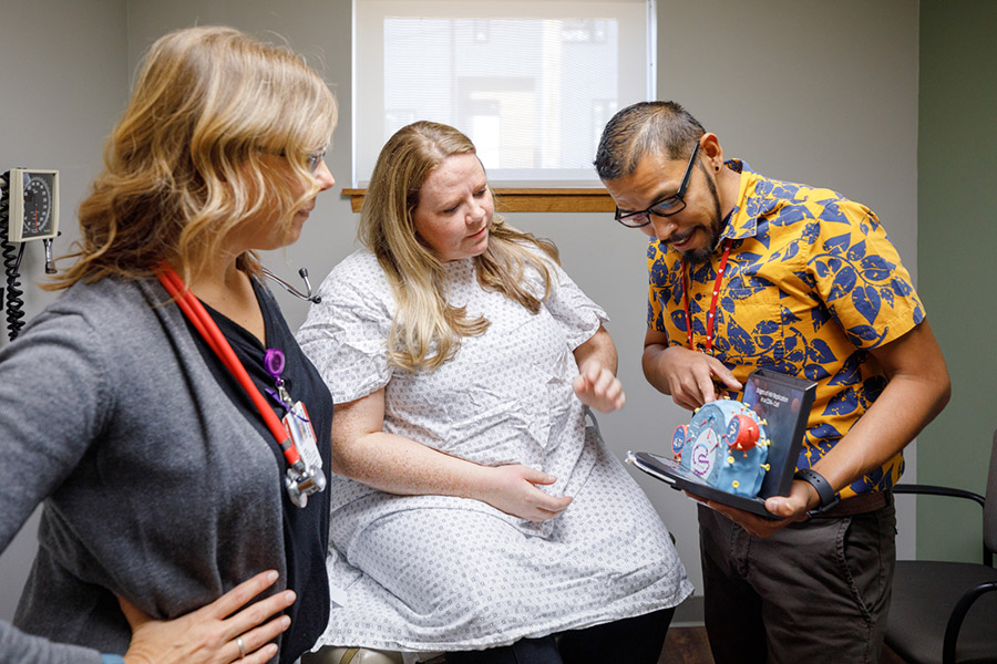 A patient looks at an HIV virus model with caregivers in UNMC's Specialty Care Clinic.