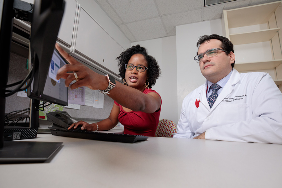Two UNMC infectious diseases faculty members work in an office setting and point at information on a computer screen.