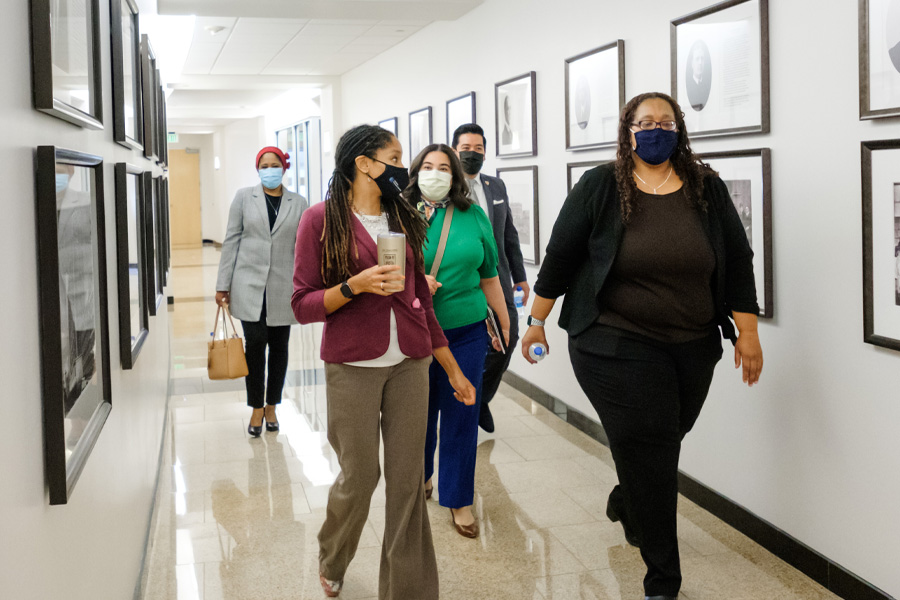 A group of people wearing surgical masks walk down a hallway