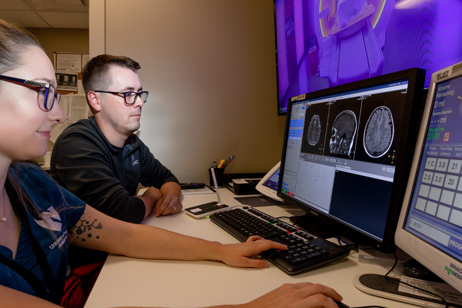 Two people review an MRI scan on a computer