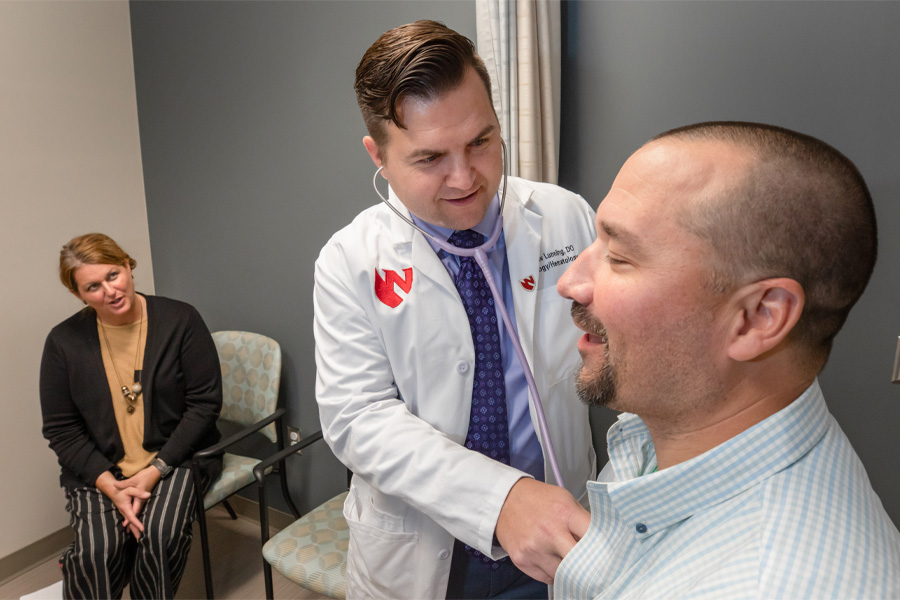 Matthew Lunning, DO, works with a patient while a family member looks on