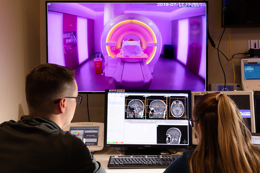 Two people review an MRI scan on a computer