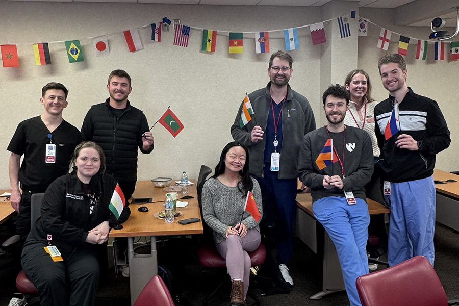 A group of residents pose in an indoor office space near small international flags during a wellness event.