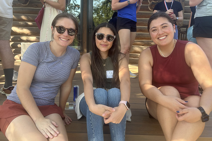 Three female residents pose outdoors on cabin stairs during a recent wellness retreat.