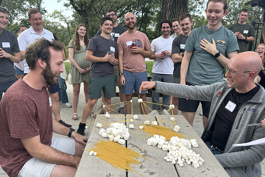 Two residents participate in a team building exercise outdoors as other residents cheer them on.