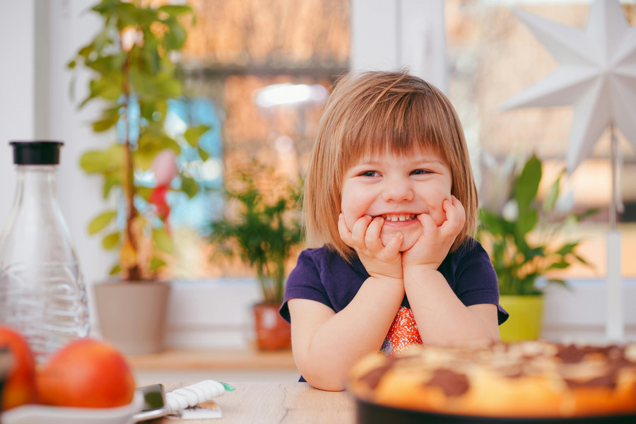 Smiling child sits at the kitchen table.