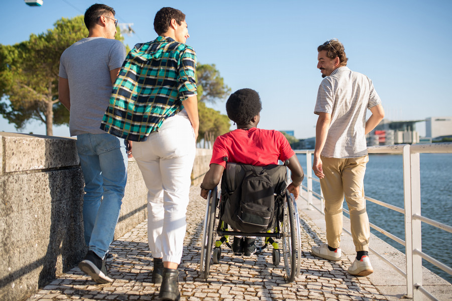 Four individuals, one in a wheelchair, on a marine boardwalk.