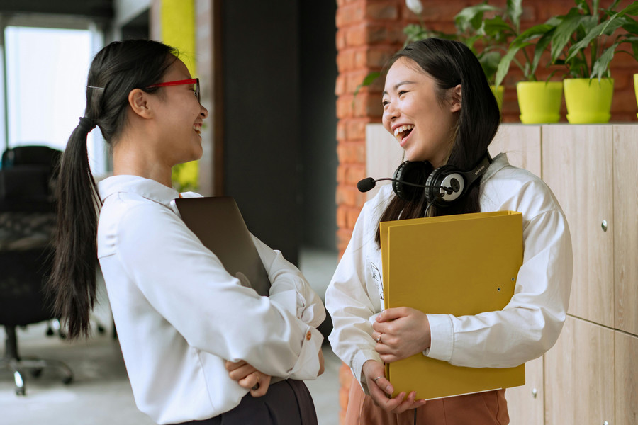 Two smiling adults talk in an office conference room.