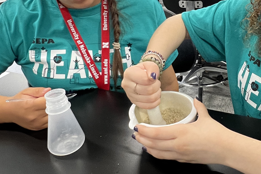 Two young students in teal SEPA shirts work on a science project.
