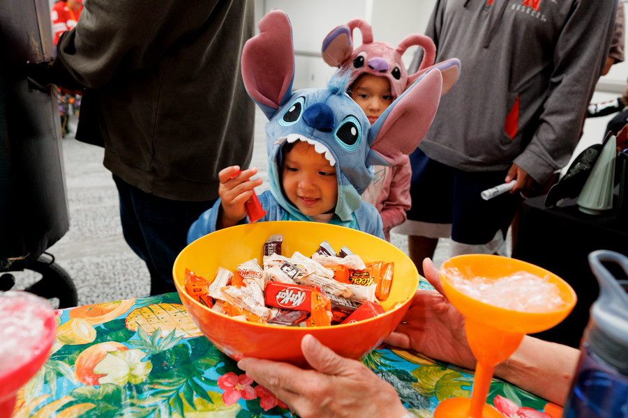 Young child in a creature costume picks out candy from a large bowl.