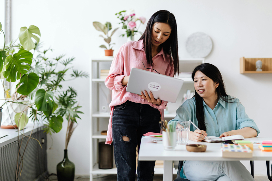 Two women review information on a laptop.