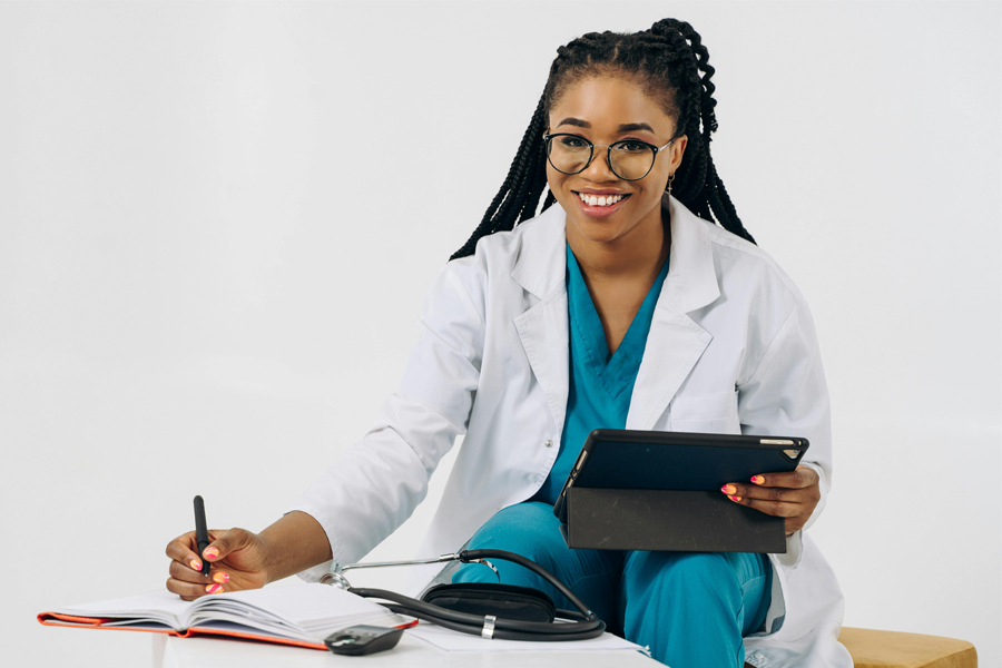 A provider sits with a tablet and documents, smiling at the viewer.