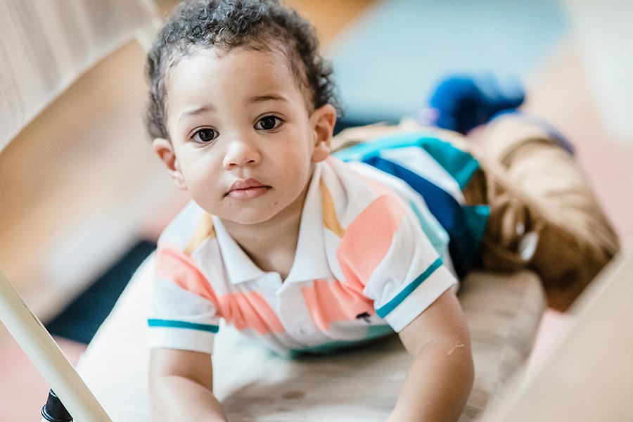 Small child crawling onto a chair.