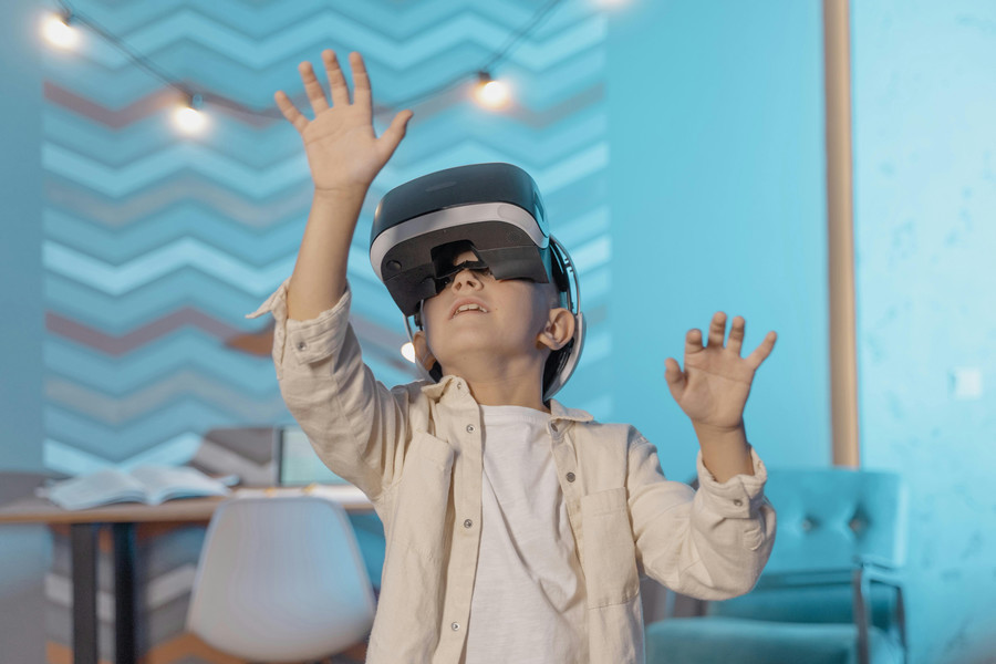 Child wearing a virtual reality headset reached over their head.