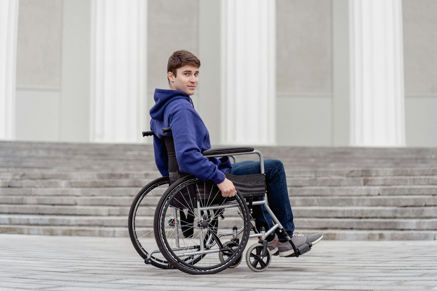 Young adult in wheelchair in front of a government building.