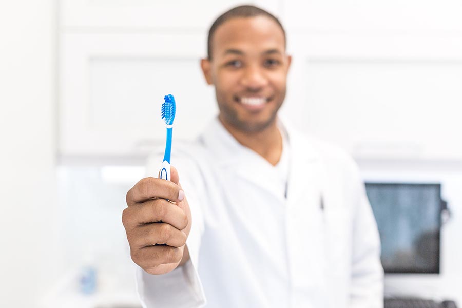 Dentist holding toothbrush towards the camera, Matthew Henry - Burst.