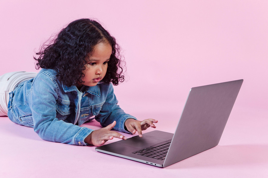 Young child plays on a laptop.
