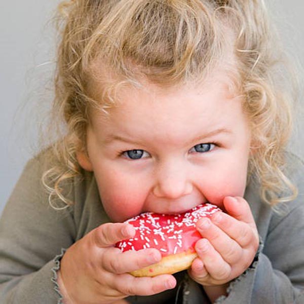 Child eating a frosted sprinkle donut, iStock.