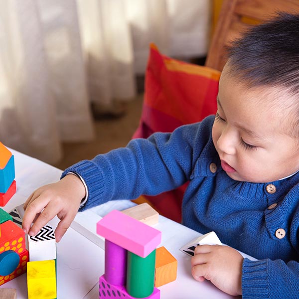 A young child playing with blocks at a table