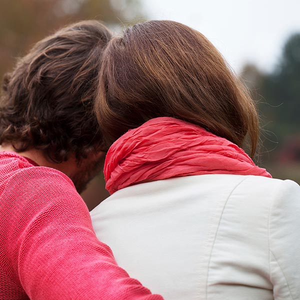 A person comforting their partner with an arm around their back, iStock.