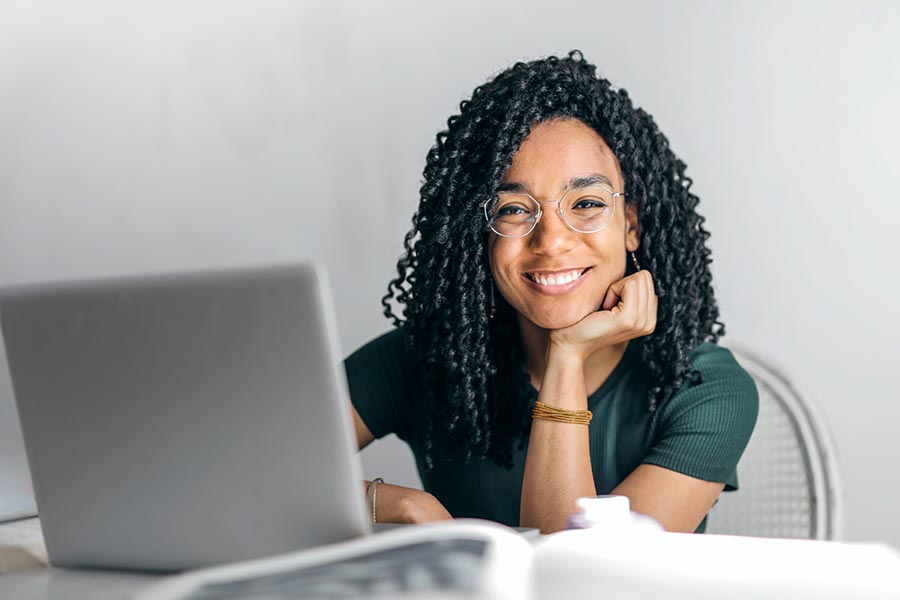 A smiling black woman sitting at a desk using a computer