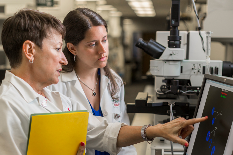 Two women discuss results on a laboratory computer.