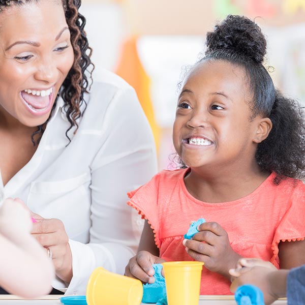 A happy young girl with autism playing with Play-Doh