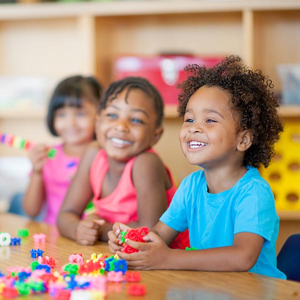 Three happy children playing with blocks at a table