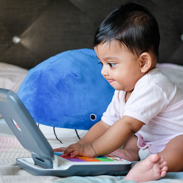 Baby using toy laptop, by Mahmud Ahsan from Unsplash.