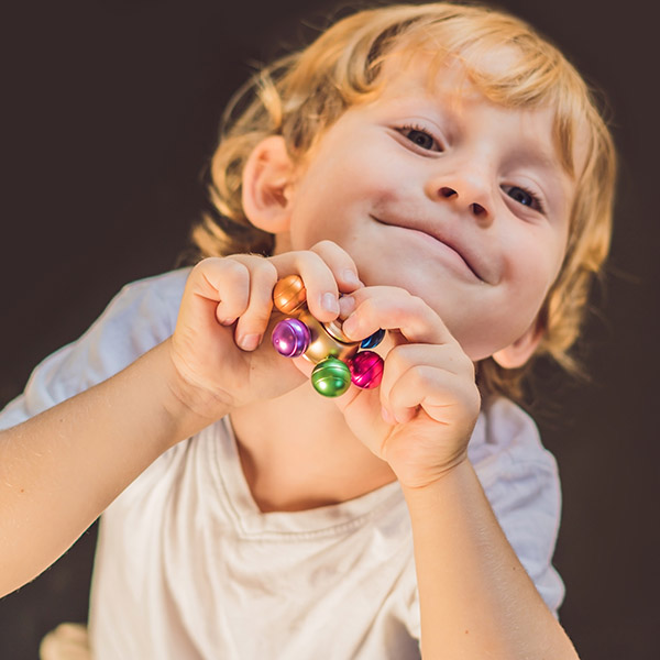 Child smiling playing with a colorful fidget, Adobe Stock. 