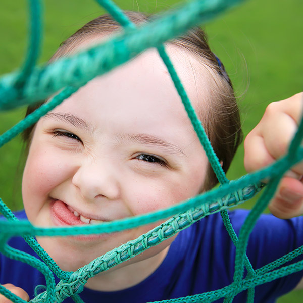 Child smiling playfully climbing on rope ladder, Shutterstock. 