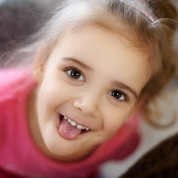 Child playfully sticking tongue out at camera, Adobe Stock.
