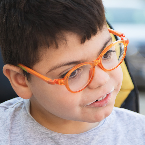 Child wearing orange glasses looks away from the camera, Adobe Stock.