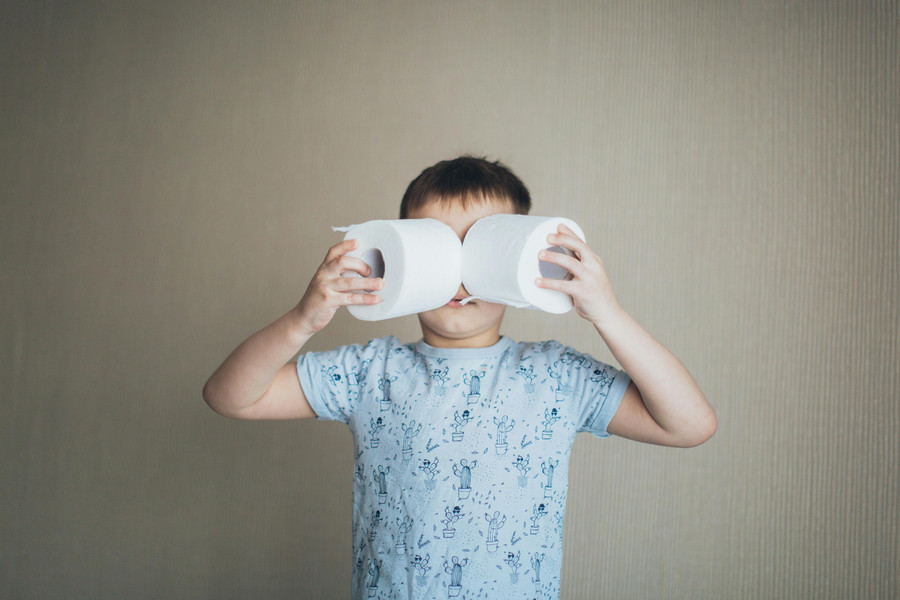 Child holding two rolls of toilet paper near his face like they're a pair of goggles.