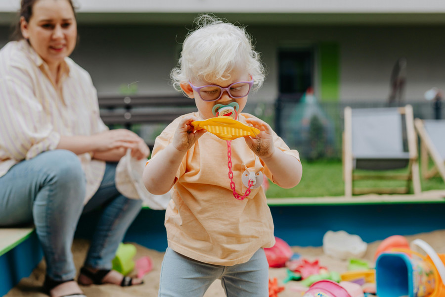 Small child with glasses holding a toy.