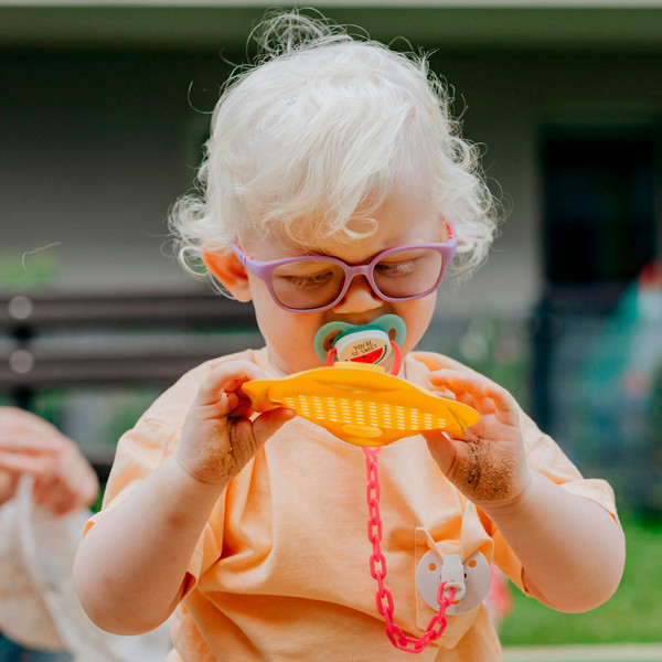 Child with glasses holding a toy.