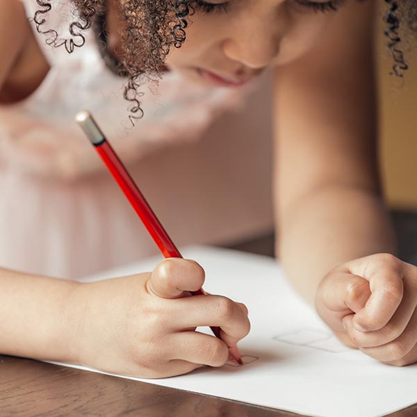 A young girl using a pencil to write on a piece of paper