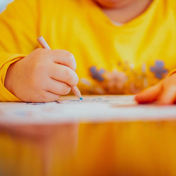 Anonymous child at desk writing on paper, Alexander Drummer - Unsplash.