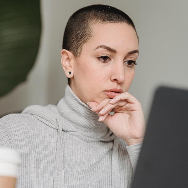 Contemplative young female provider watching webinar on laptop, by George Milton – Pexels.